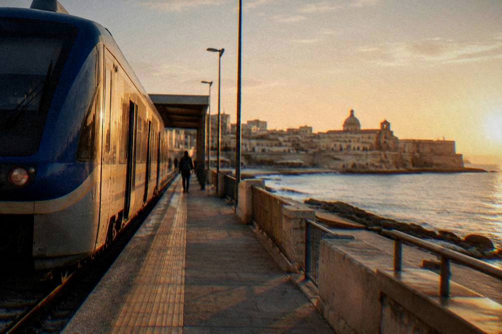A regional train waiting at an Italian station platform in early morning light