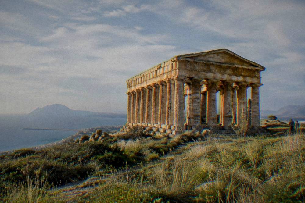 Ancient stone temple standing on a hillside among wild grasses