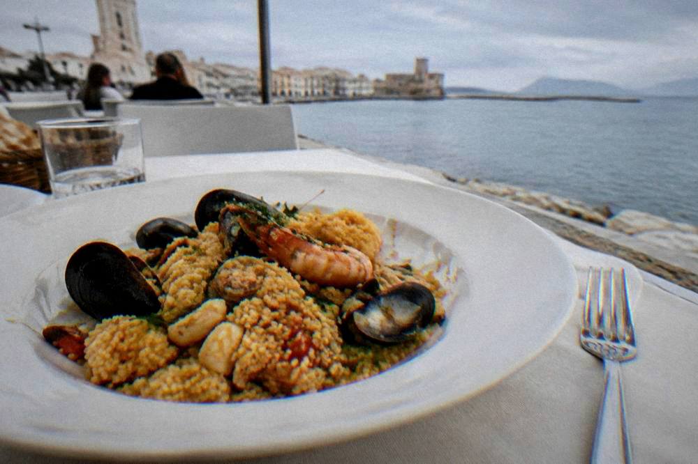 Seafood couscous plated in a restaurant with a fork beside it