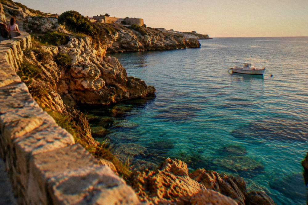 Turquoise cove with rocky cliffs and a small boat anchored offshore