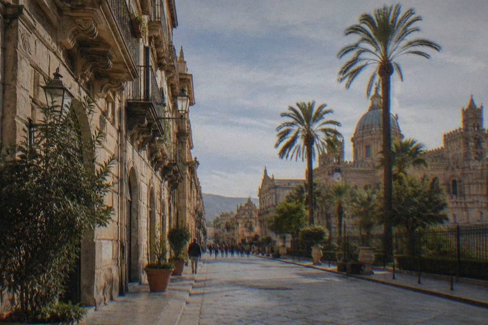 A sunny street in the historic centre of Palermo with ornate buildings and palm trees