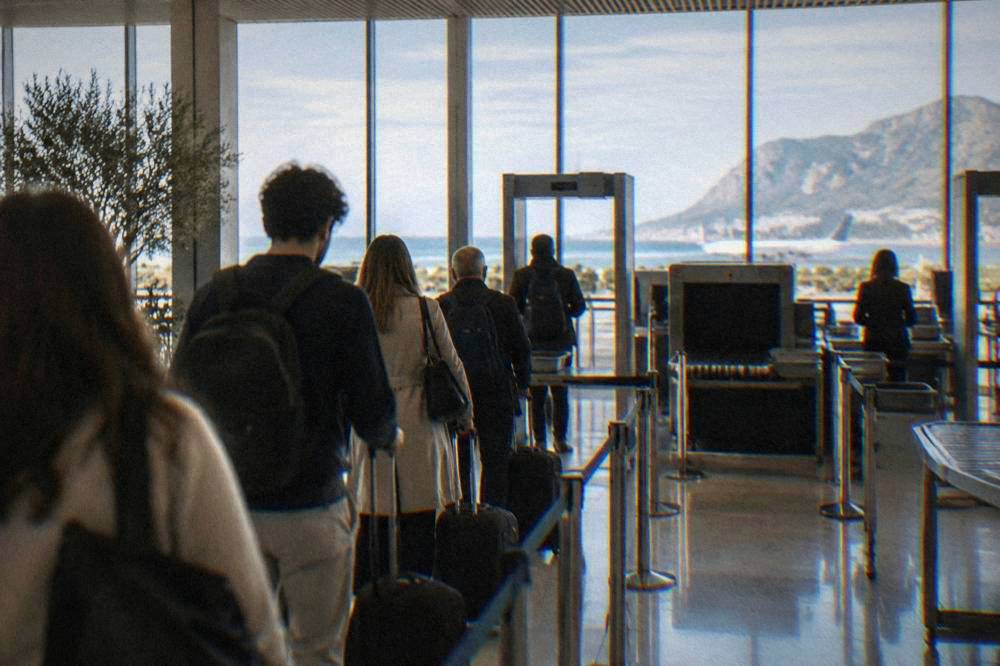 Travellers with suitcases queuing at an airport security checkpoint