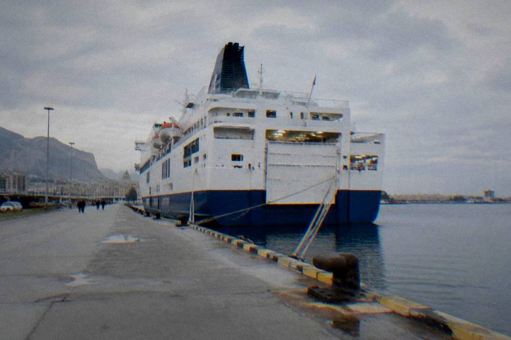 A large overnight ferry docked at a city waterfront in early morning light
