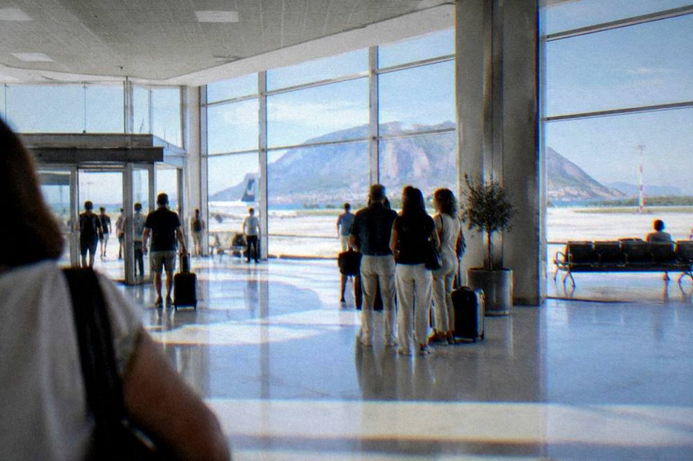 A bright airport arrivals hall with travellers gathering at a meeting point