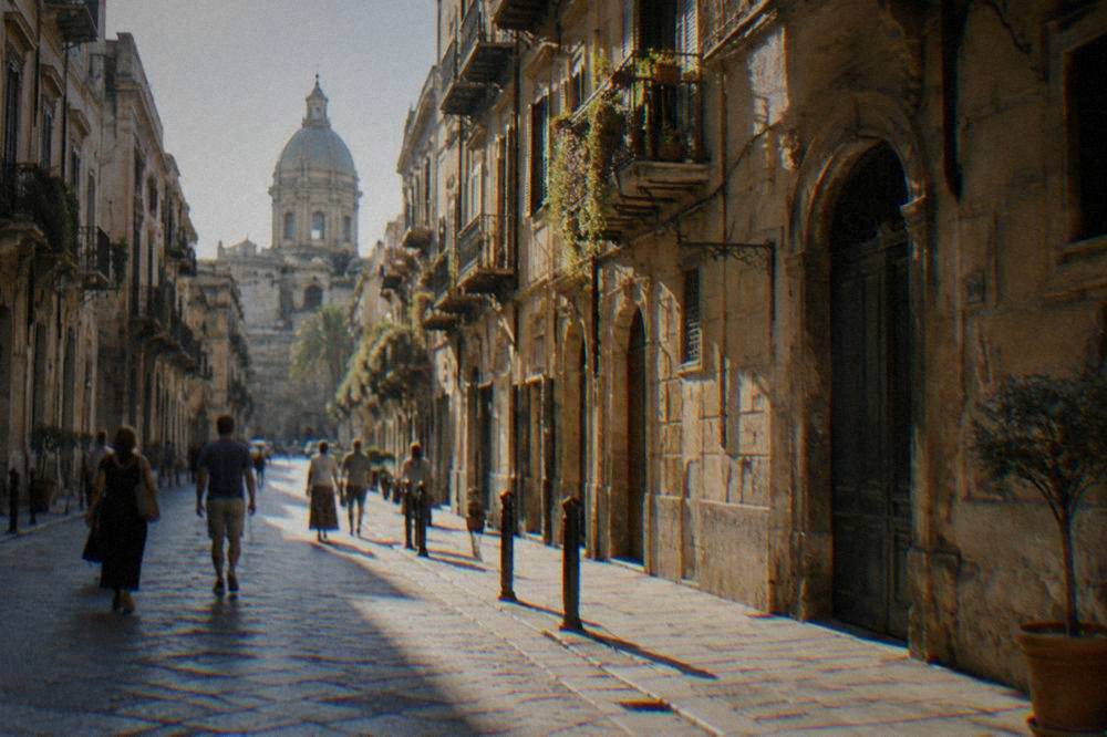 Pedestrians crossing a narrow Palermo street lined with old palazzi