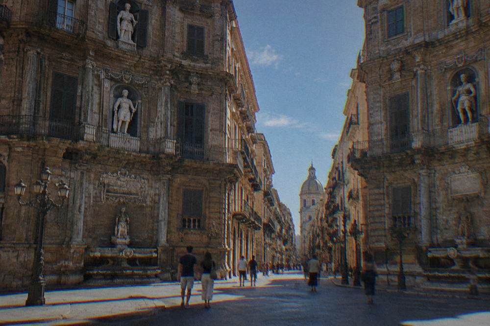People strolling under ornate building facades at the Quattro Canti crossing in Palermo