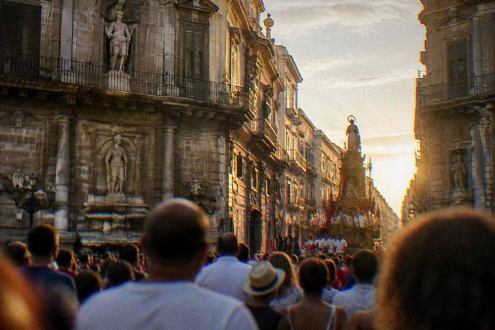 A crowd watching the Festino chariot procession along the Cassaro in Palermo in July