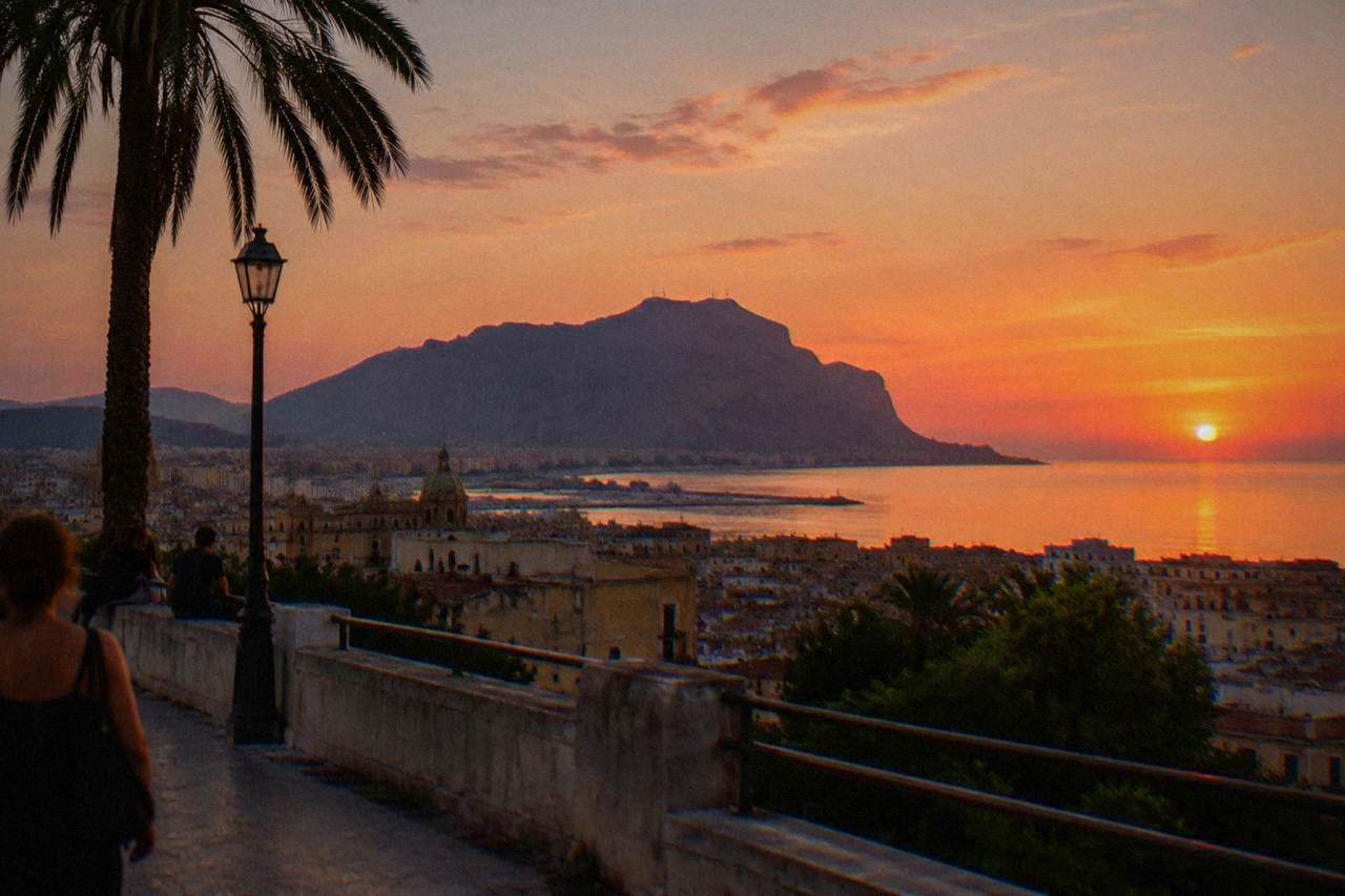 Evening view over Palermo rooftops toward the sea with Monte Pellegrino in the distance