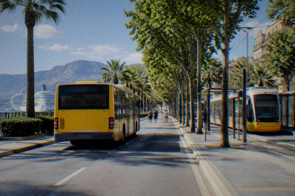 A yellow Palermo city bus and a tram at a stop on a tree-lined street in the city centre