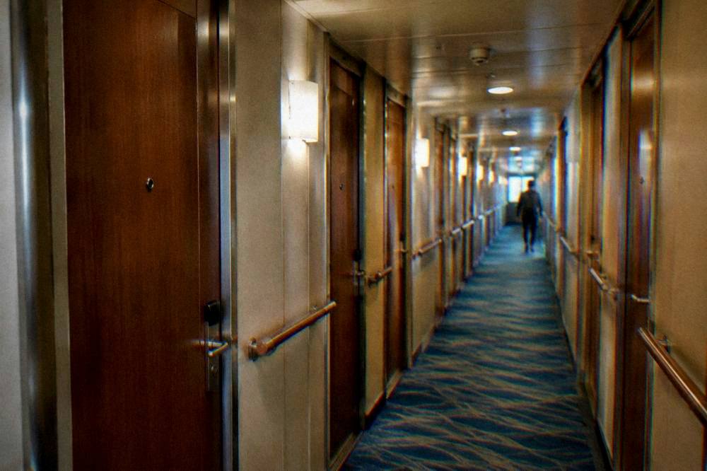 The interior of a ferry ship corridor with cabin doors on both sides and soft lighting