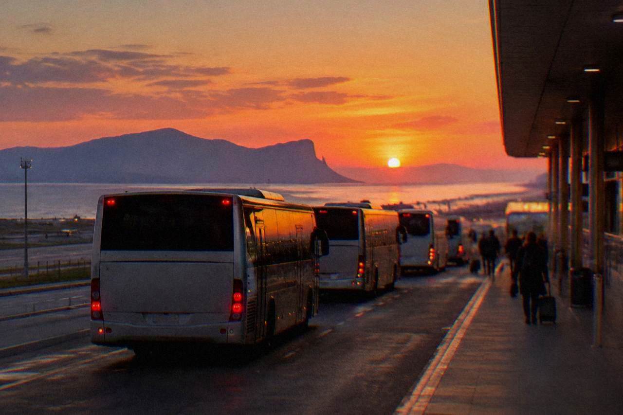 Buses lined up at the terminal curb of Palermo Falcone Borsellino Airport at dusk