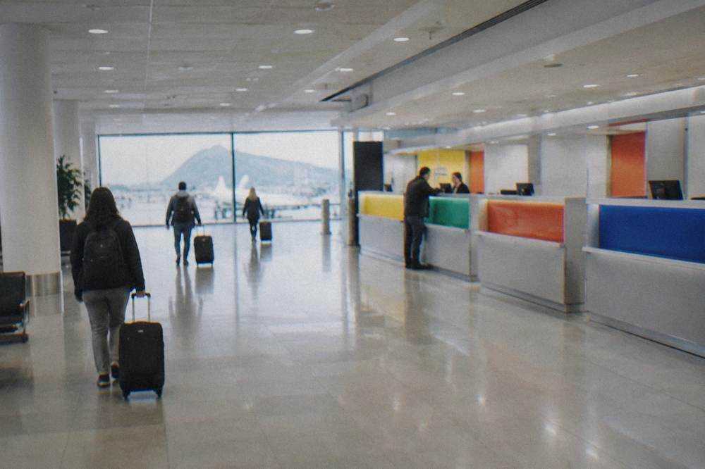 A bright airport arrivals hall with a row of car rental desks