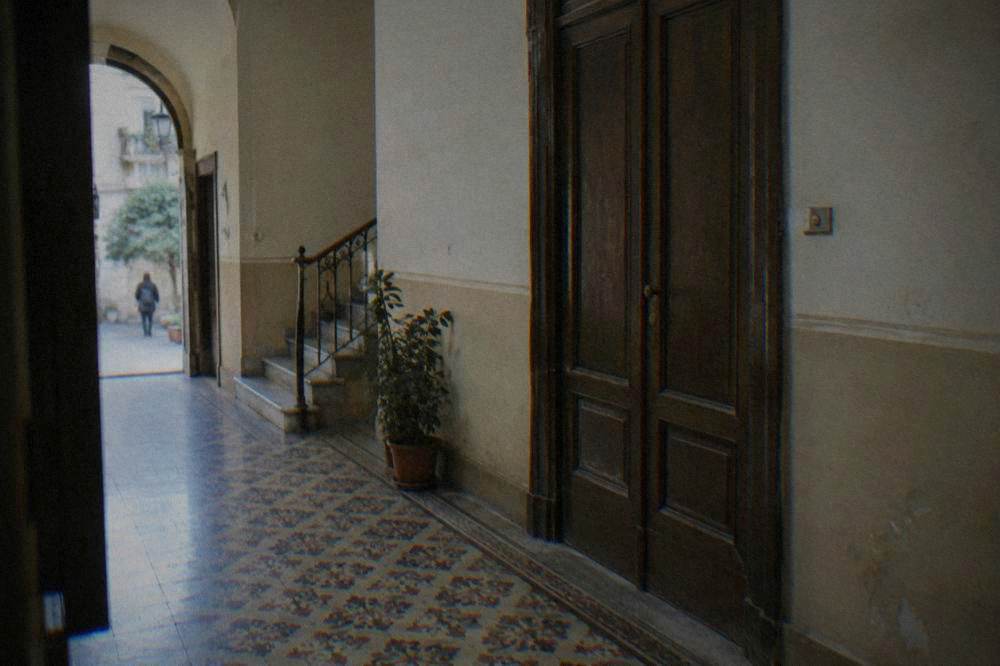 A Palermo apartment entrance hall with patterned floor tiles and a heavy wooden door