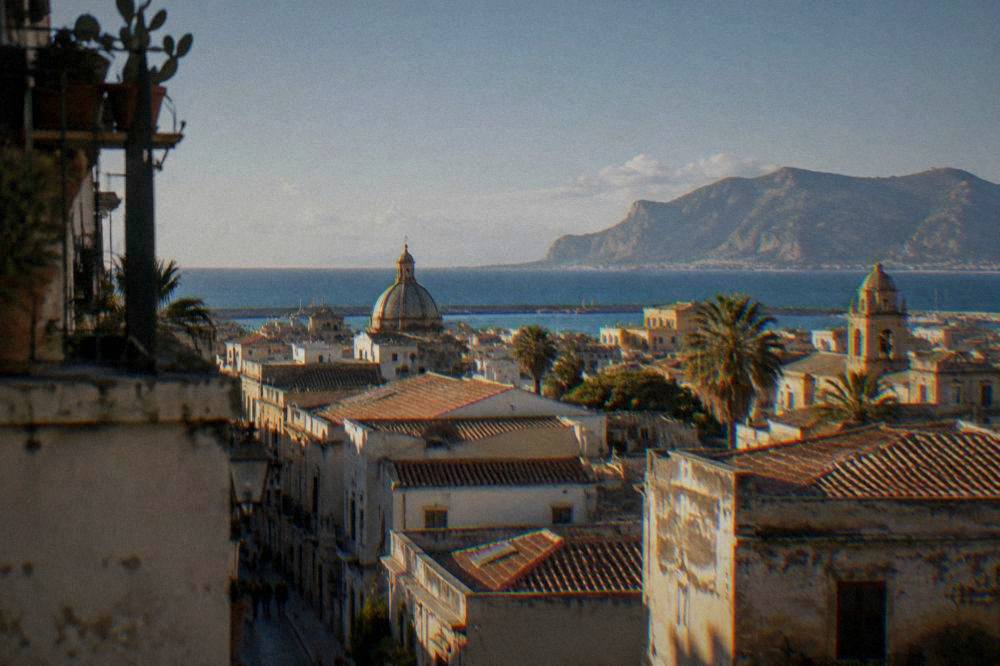 A view over Palermo rooftops toward the sea with distant mountains