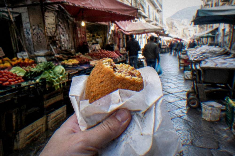 Arancina wrapped in paper on a Palermo street