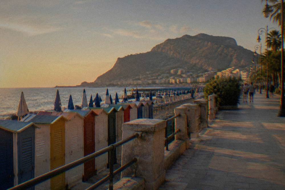 Rows of coloured changing cabins and parasols along a seafront promenade