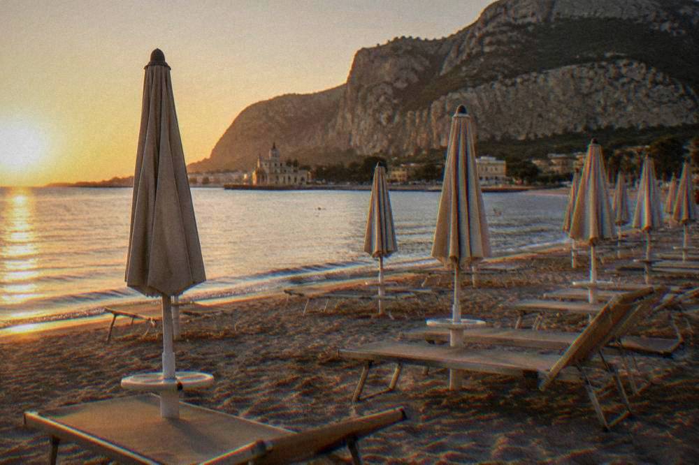 Empty beach loungers and parasols on sand in early morning light