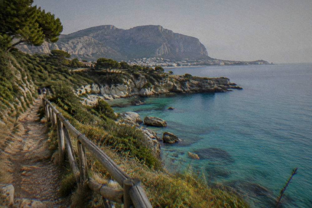 A coastal nature reserve path with turquoise coves below limestone cliffs