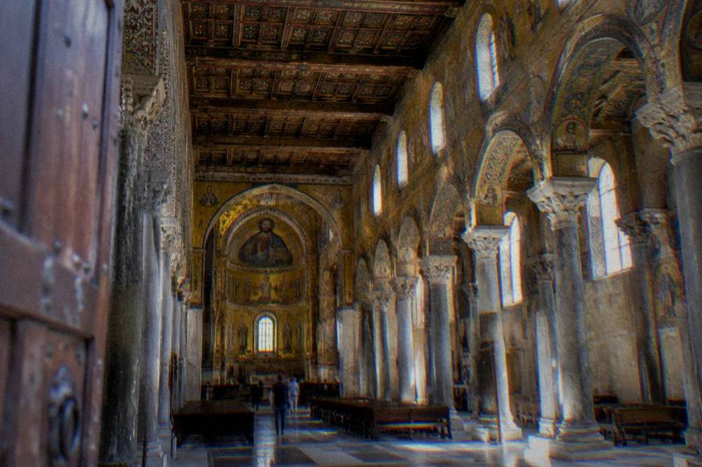 Painted wooden ceiling and stone nave of the Cappella Palatina seen from the entrance