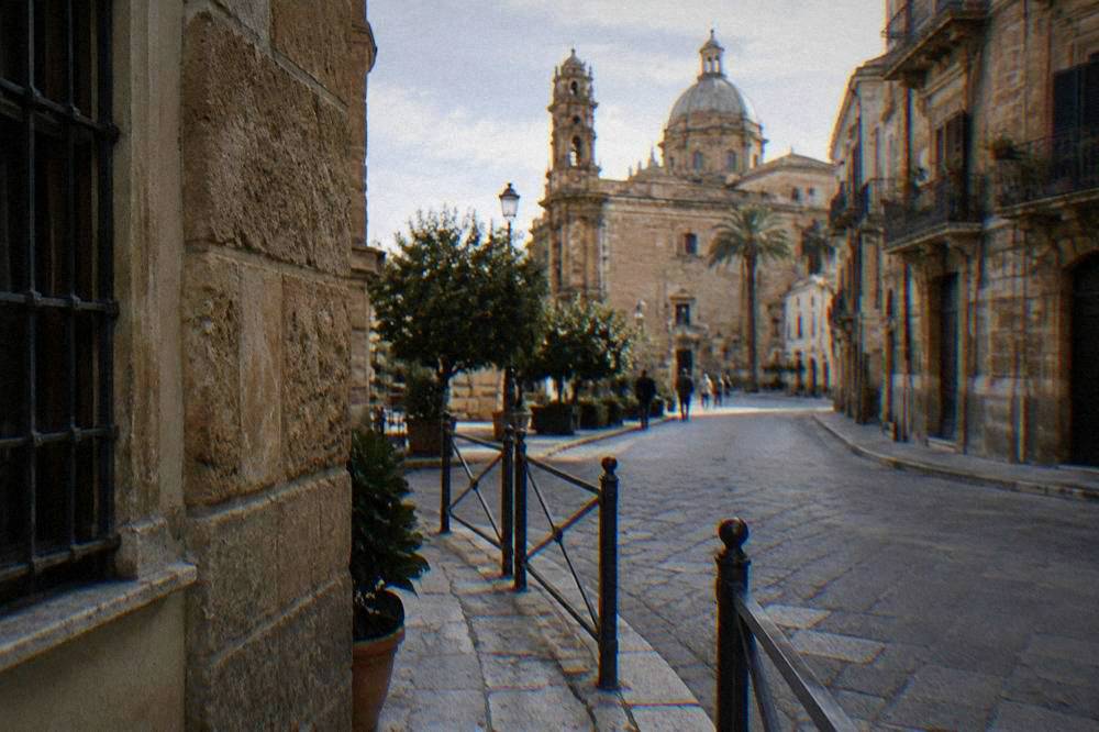 A narrow Palermo street corner with a low barrier at the edge of a limited traffic zone