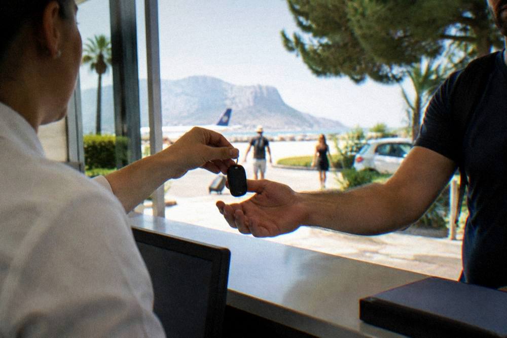 A rental car key handover at an airport desk counter