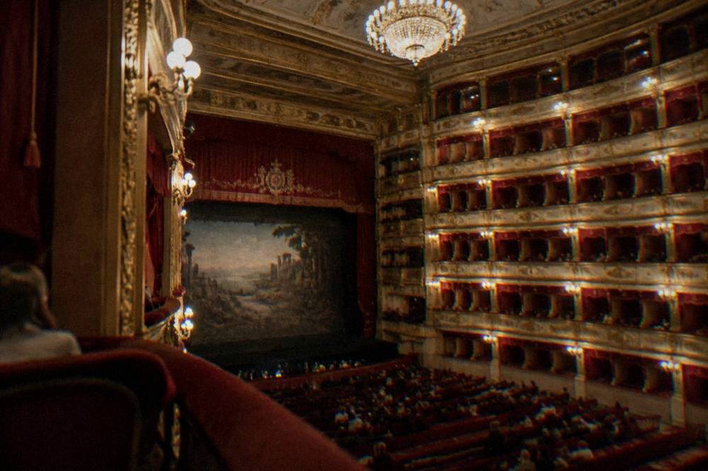 The grand auditorium of an ornate opera house in Palermo, with tiers of boxes and a chandelier