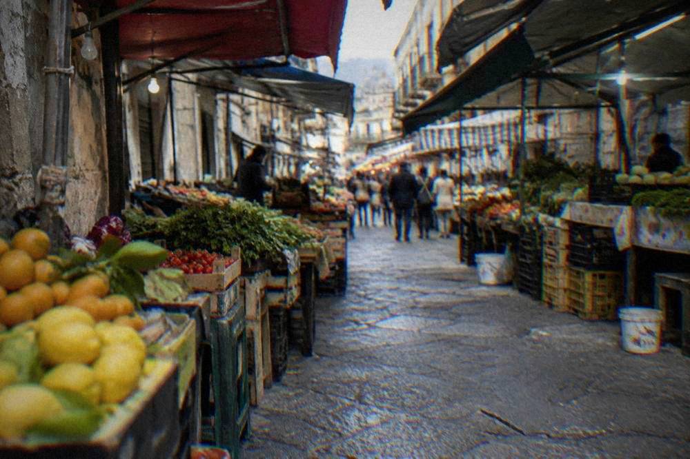 A covered market lane in Palermo with produce stalls on both sides