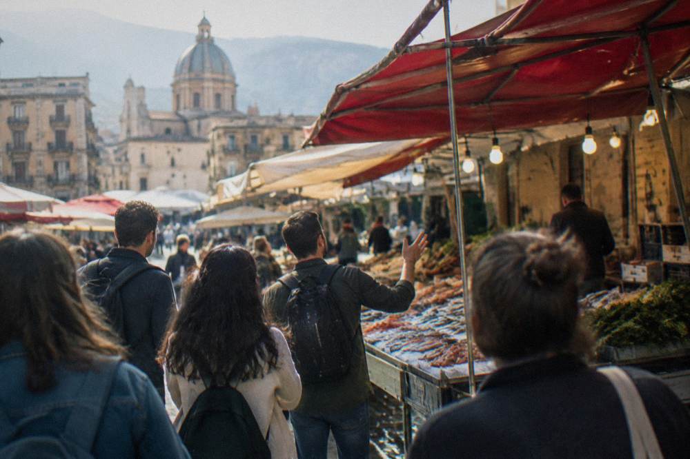 A guide talking to a small group at a food stall in a Palermo market