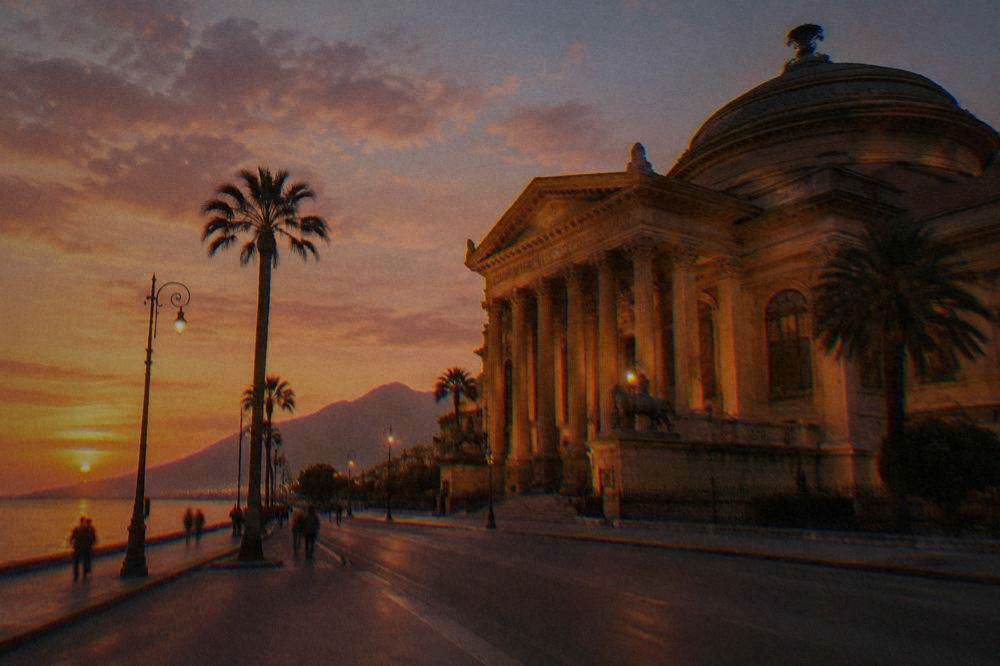 A grand theatre facade lit at dusk on a Palermo avenue