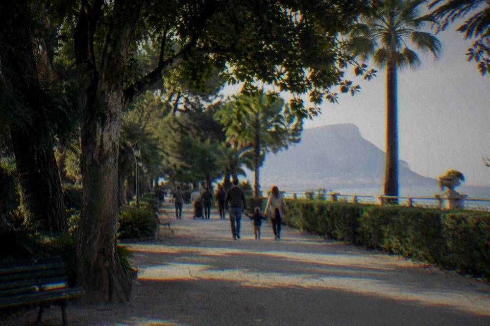 Families strolling under trees in a Palermo public garden