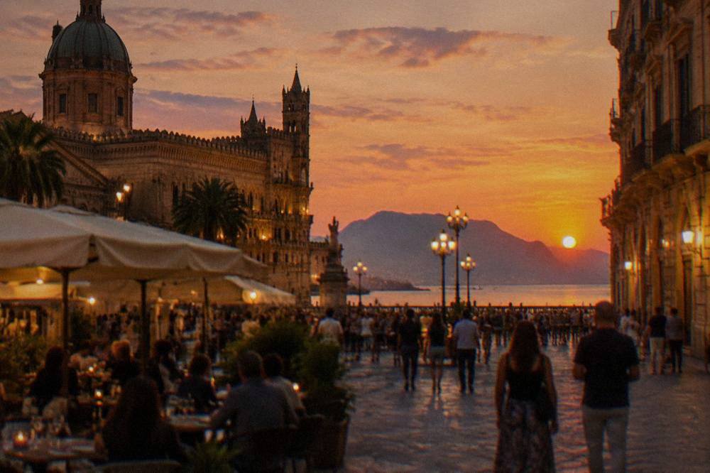 Evening crowd at a lit-up square in Palermo with café tables and historic facades