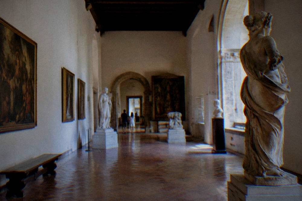 Gallery hall in a Palermo museum with sculptures and paintings under soft winter light