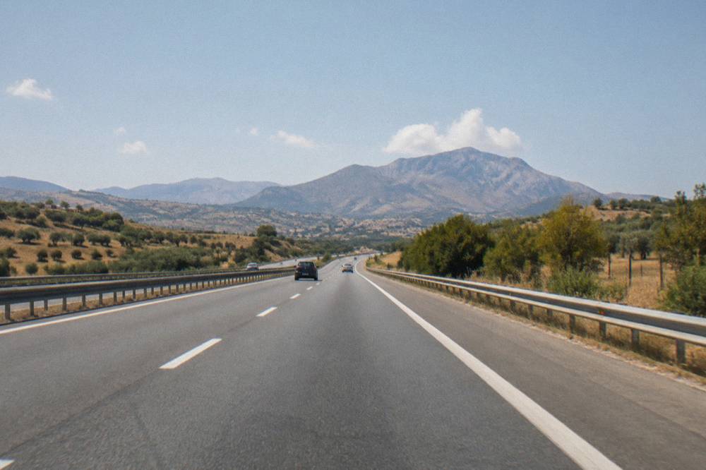 A wide Sicilian motorway cutting through open countryside toward distant hills