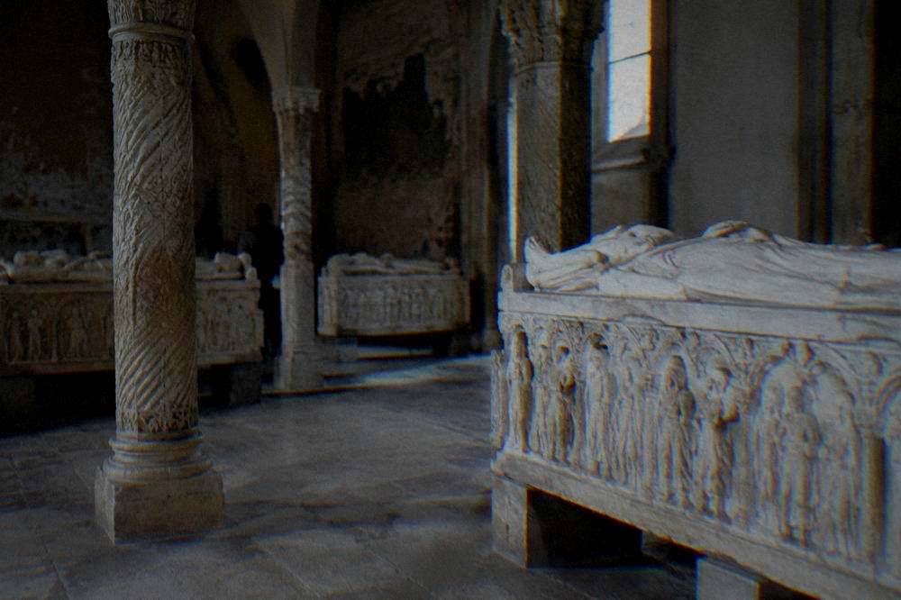Stone sarcophagi displayed in a dimly lit chapel with carved columns