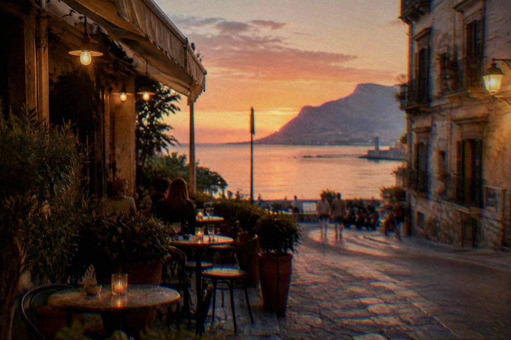 Lit bar terrace with small tables on a Palermo street in the evening