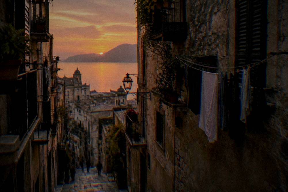 A narrow Palermo alley with washing lines and old stone facades in the evening