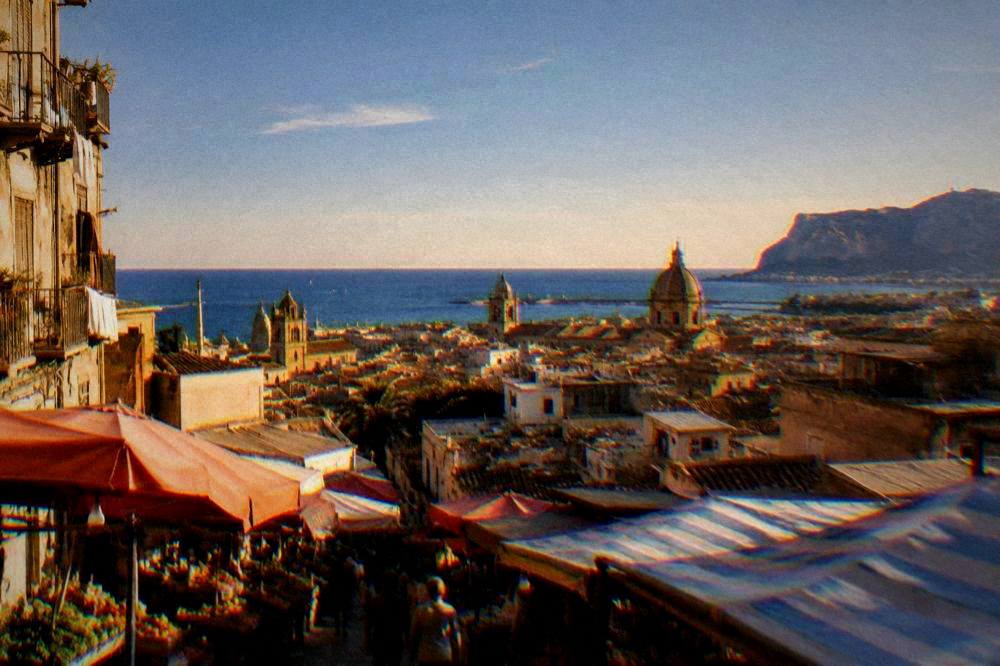 A wide view over Palermo rooftops toward the sea at golden hour