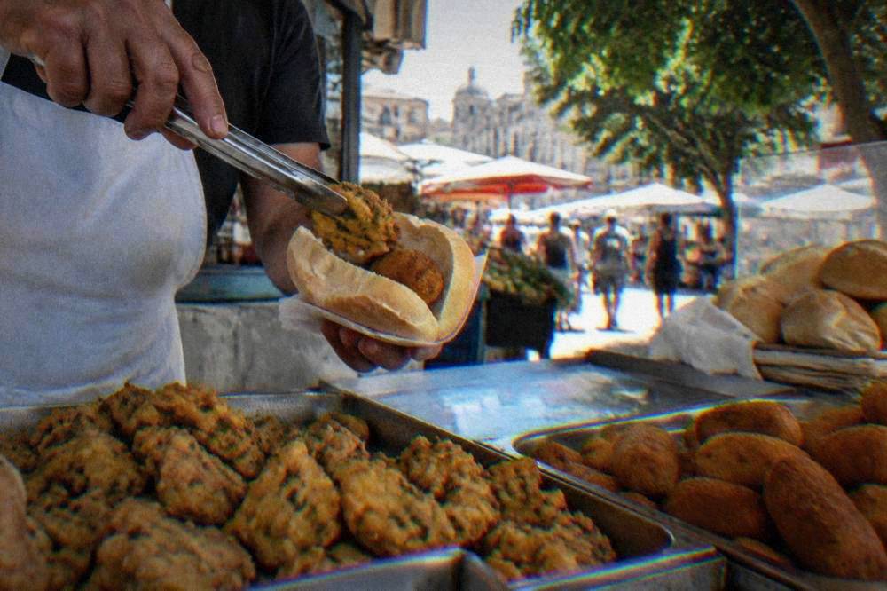 Chickpea fritties and potato croquettes being served in a bread roll at a market counter