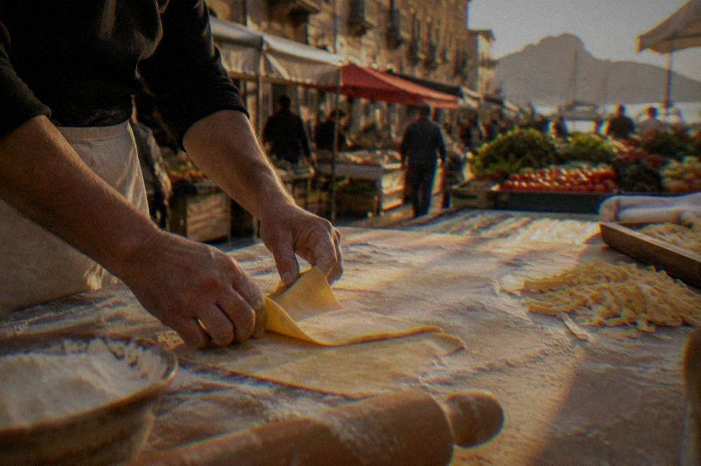 Hands preparing fresh pasta dough on a floured wooden table