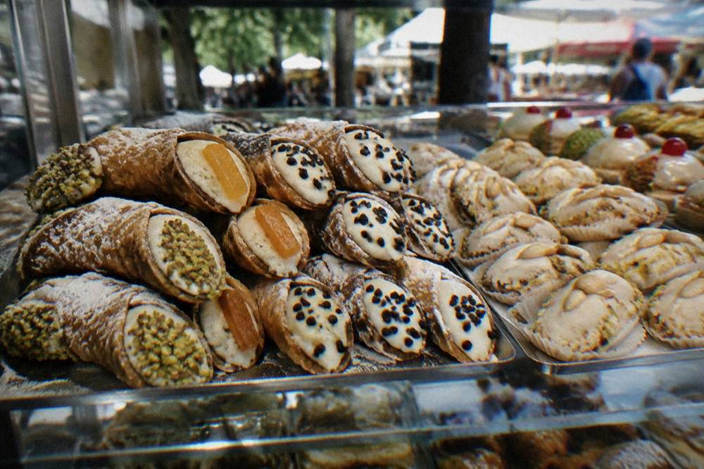 Cannoli and small almond pastries arranged in a glass bakery counter