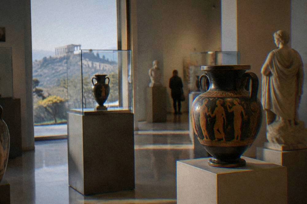 A museum gallery displaying ancient Greek pottery and stone sculpture