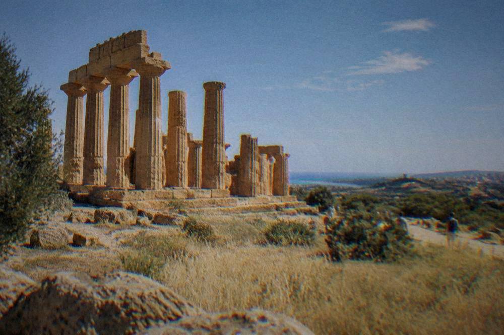Temple columns and dry grassland under a clear blue sky in southern Sicily