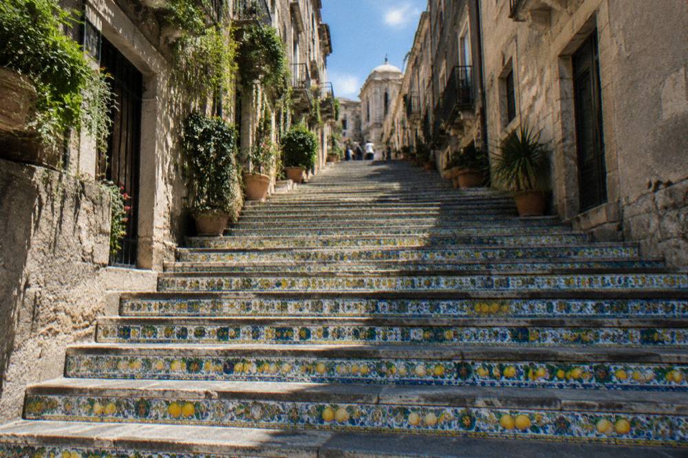 A hill town with a decorated ceramic staircase rising between old stone buildings