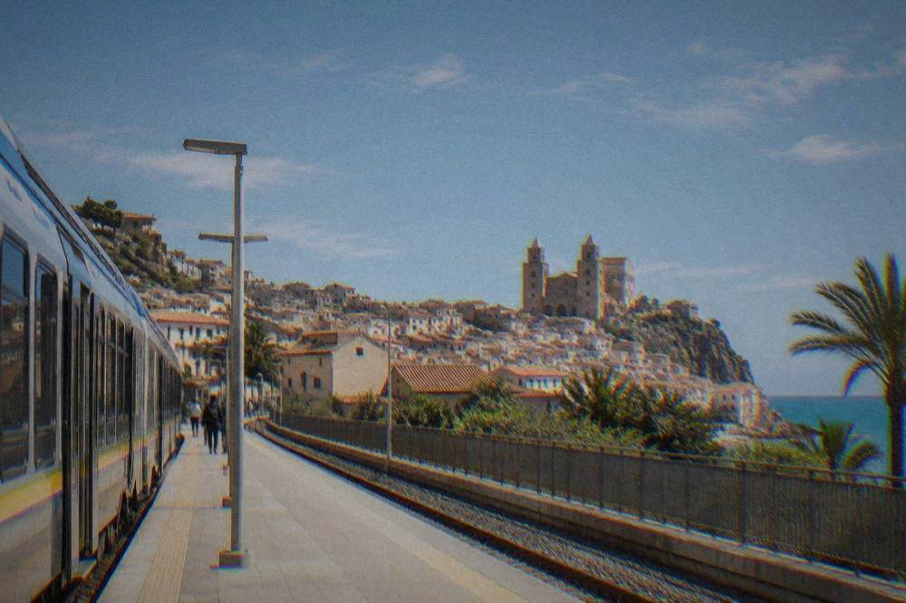 Cefalu railway station platform with a regional train and the town's rooftops behind