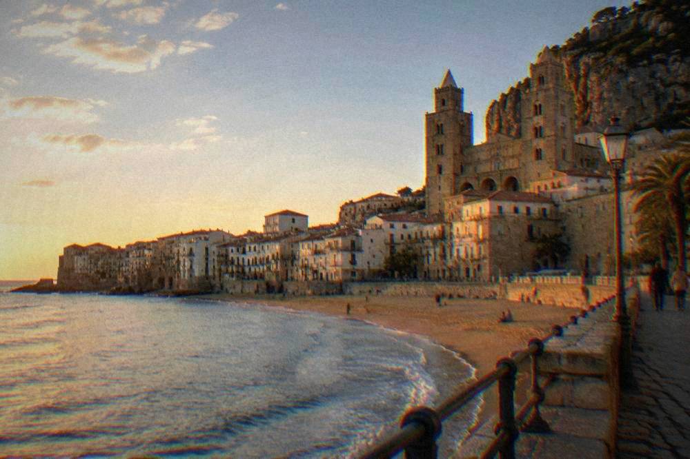 The seafront promenade of Cefalu with the long sandy beach and the town behind it