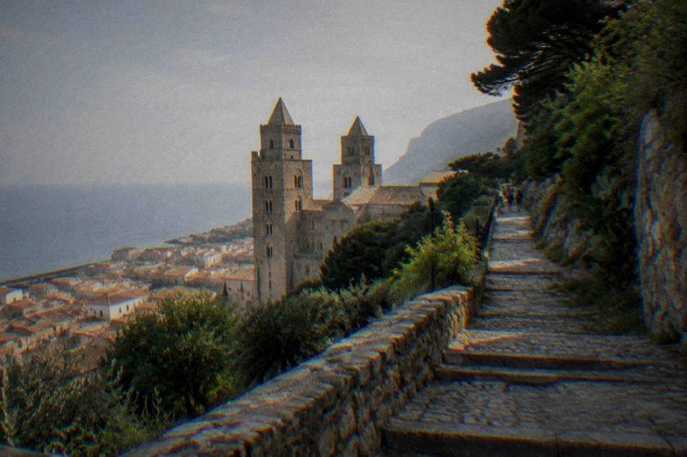 Stone steps and a path climbing up the green slopes of La Rocca above Cefalu