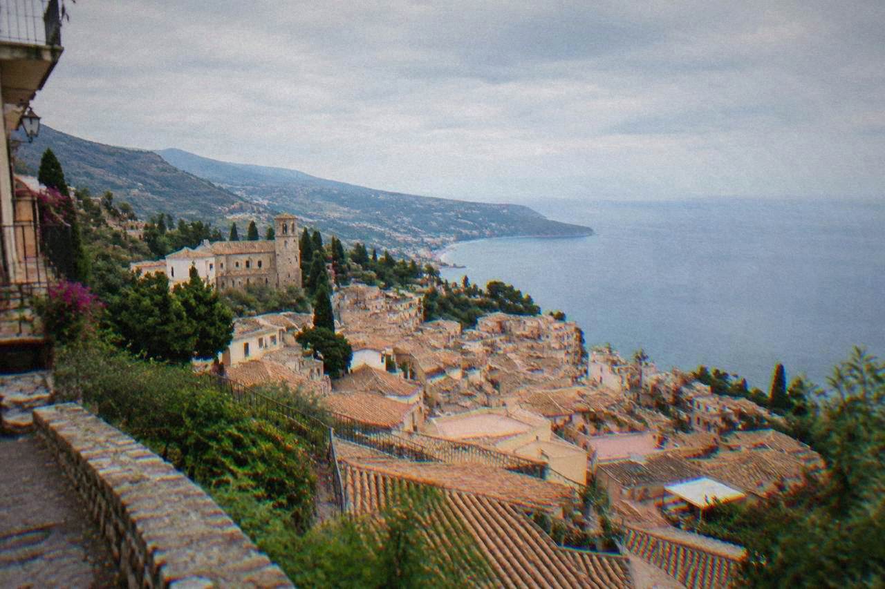 The hillside town of Taormina seen from above with terracotta roofs and the sea beyond