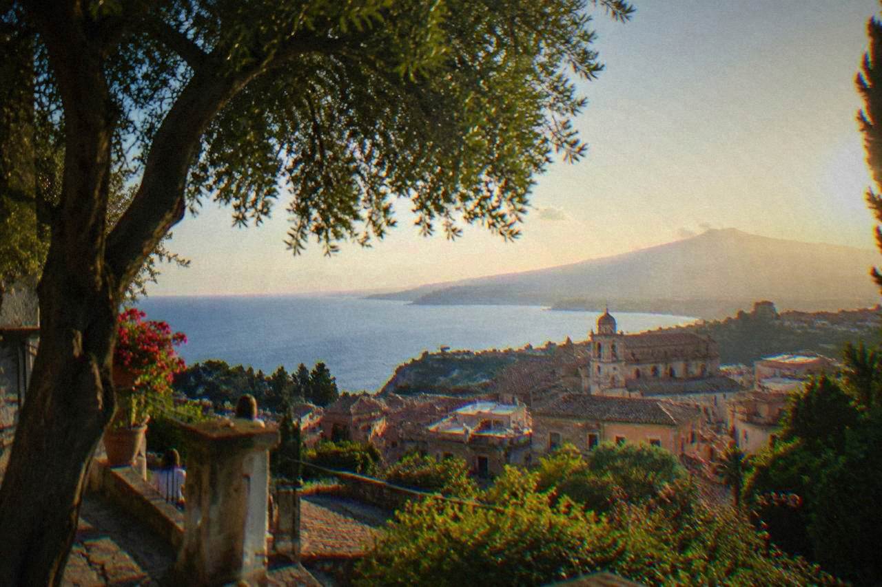 View over Palermo rooftops toward the sea and distant mountains at golden hour