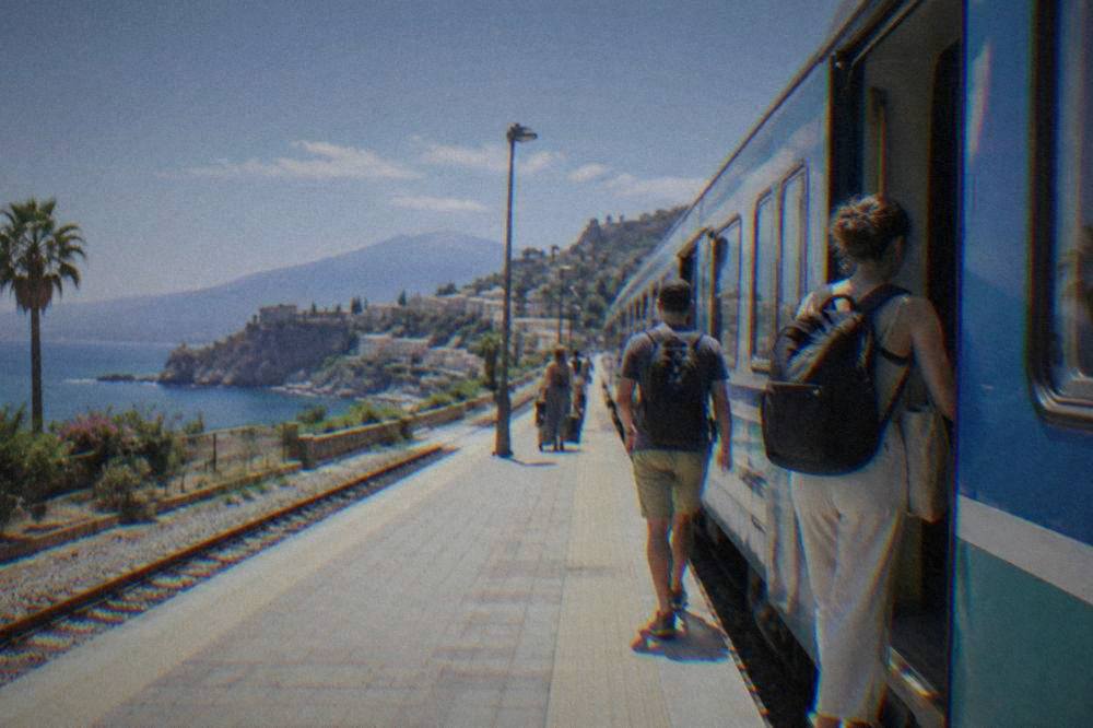 Travellers boarding a regional train at a Sicilian railway station platform