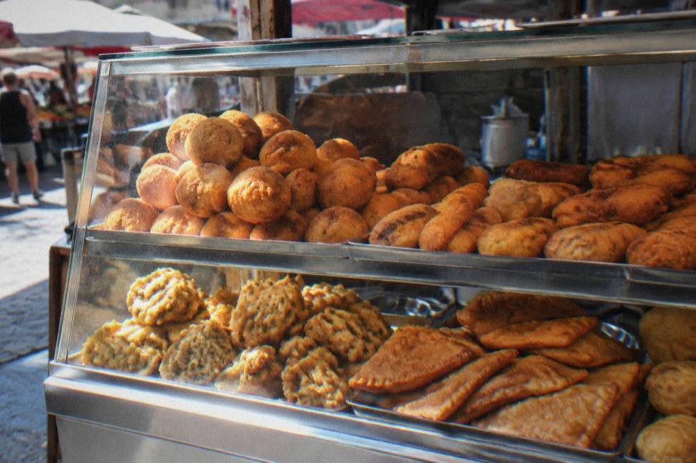 Street food stall in a Palermo market with fried snacks displayed in a glass case